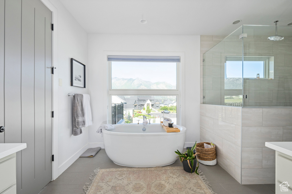 Bathroom featuring vanity, a tile shower, a soaking tub, tile patterned flooring, and baseboards