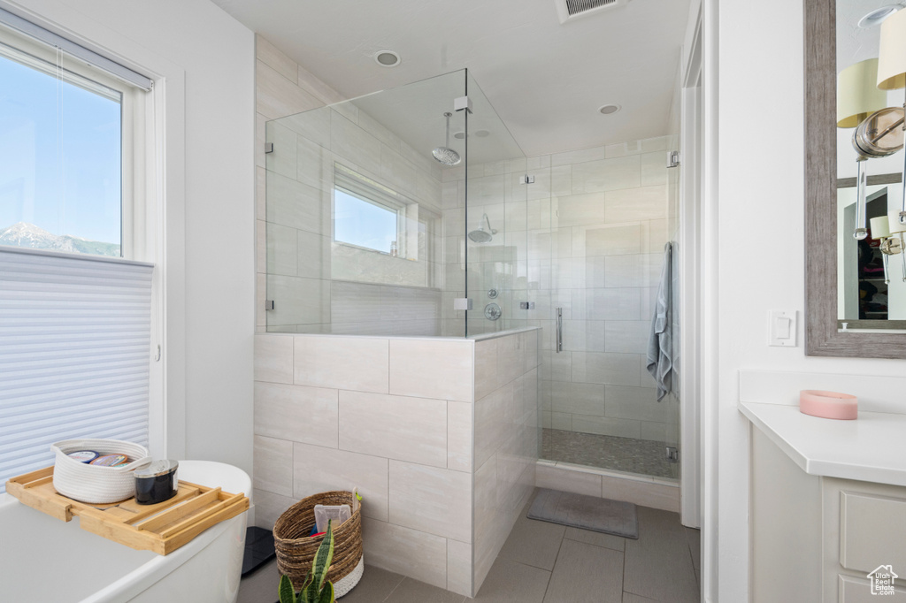 Bathroom with a stall shower, tile patterned floors, and vanity