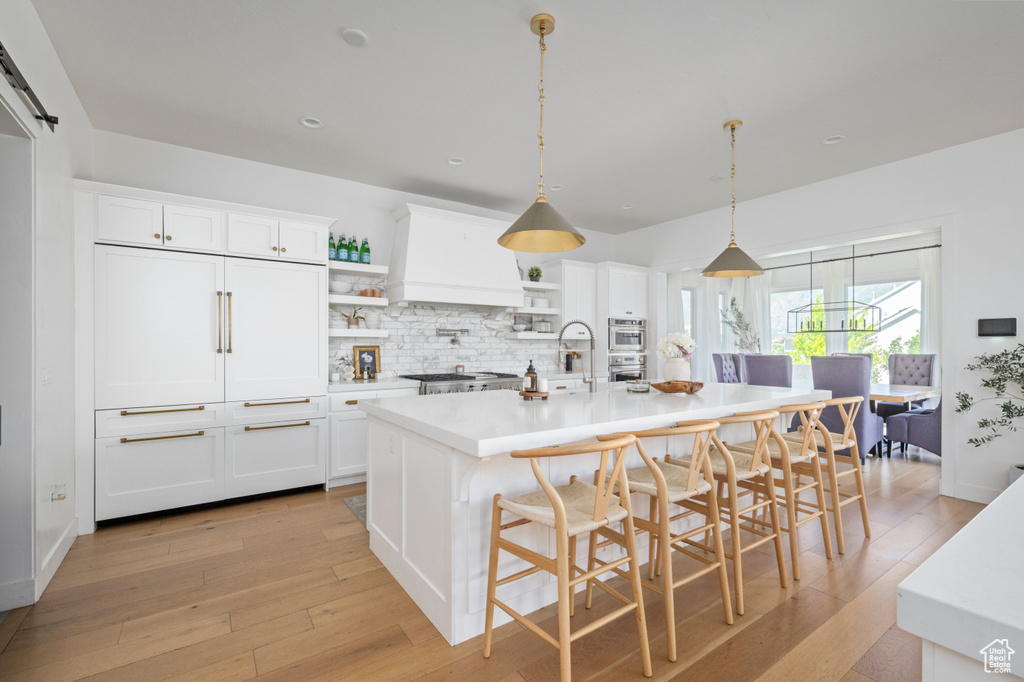 Kitchen with open shelves, light wood-type flooring, light countertops, white cabinetry, and recessed lighting