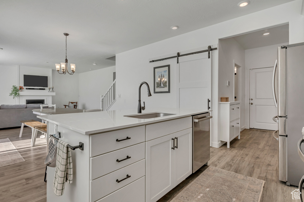 Kitchen with a sink, stainless steel appliances, a barn door, white cabinets, and open floor plan