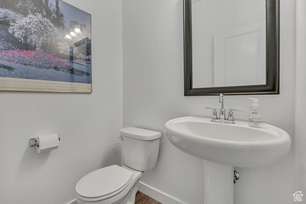 Bathroom featuring baseboards, toilet, and wood finished floors