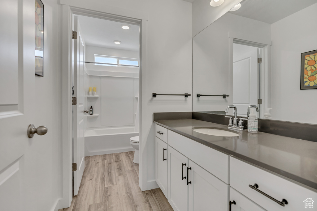 Bathroom with vanity, toilet, wood finished floors, and washtub / shower combination