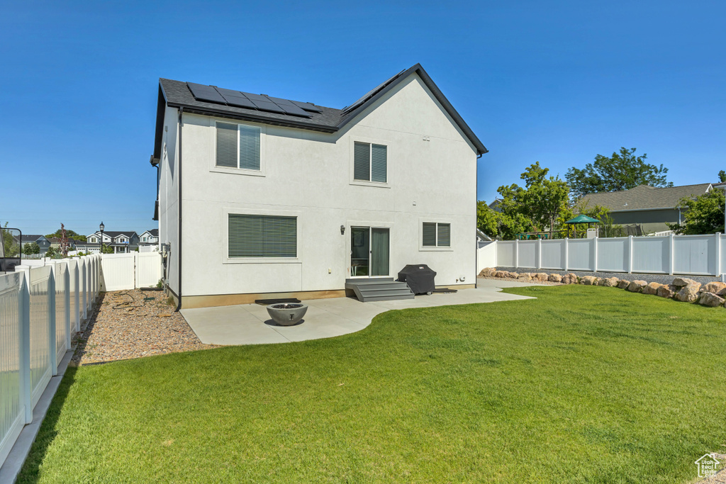 Rear view of property with a patio, solar panels, and stucco siding