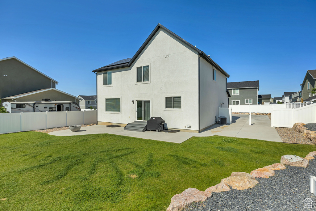 Rear view of house with a patio area, entry steps, stucco siding, and roof mounted solar panels