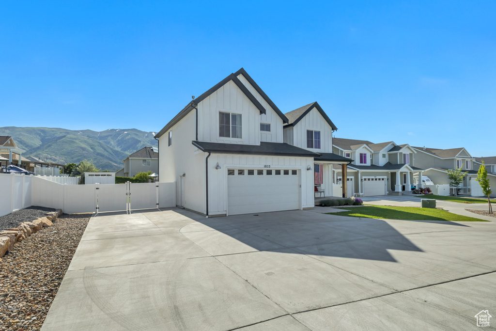 View of front of home featuring board and batten siding, an attached garage, a gate, concrete driveway, and a mountain view
