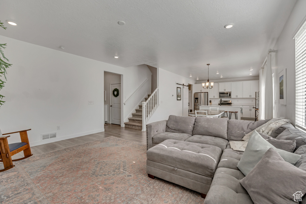 Living area with stairway, a chandelier, light wood finished floors, healthy amount of natural light, and recessed lighting