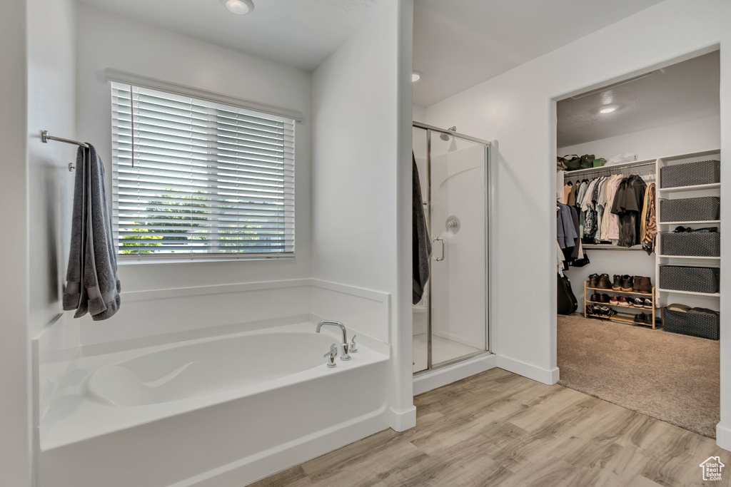 Bathroom featuring a shower stall, a garden tub, a walk in closet, and wood finished floors