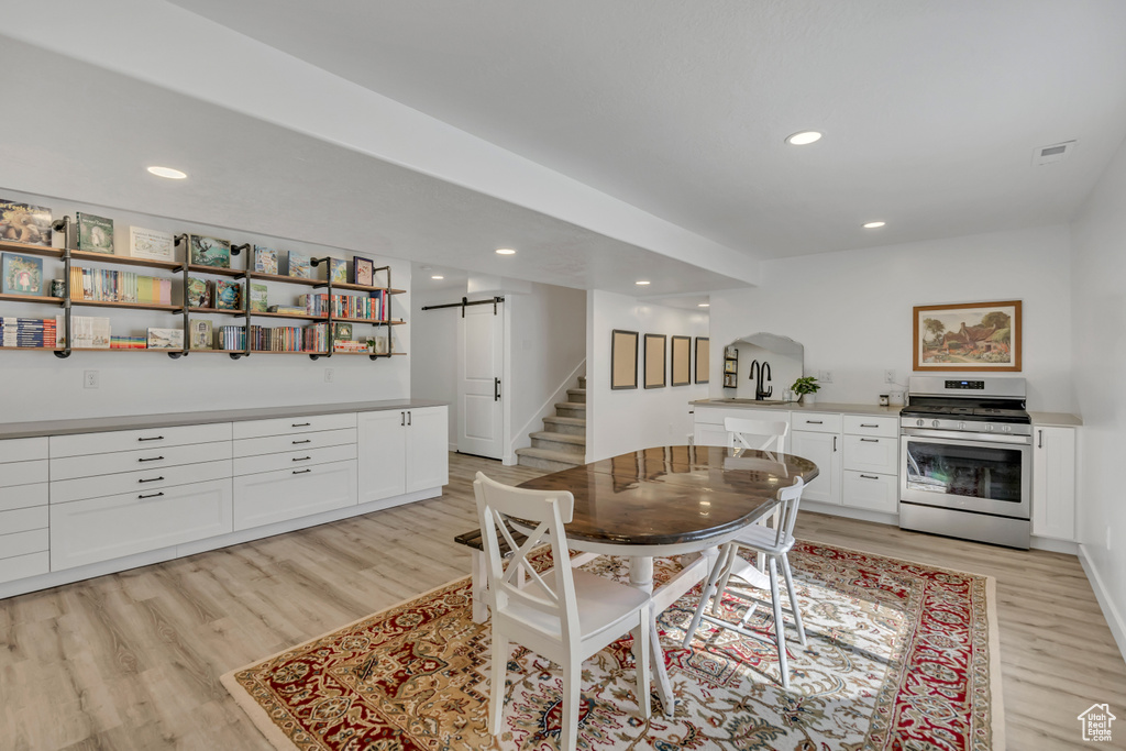 Dining room with a barn door, light wood-style floors, stairs, recessed lighting, and arched walkways