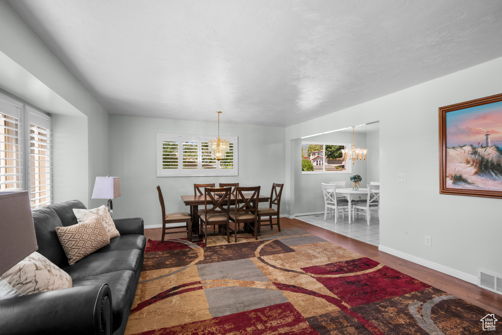 Living room featuring a chandelier, healthy amount of natural light, wood finished floors, and baseboards