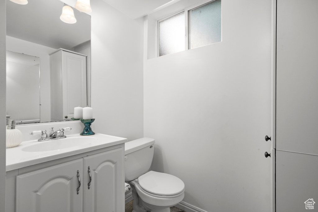 Bathroom featuring toilet, vanity, and baseboards