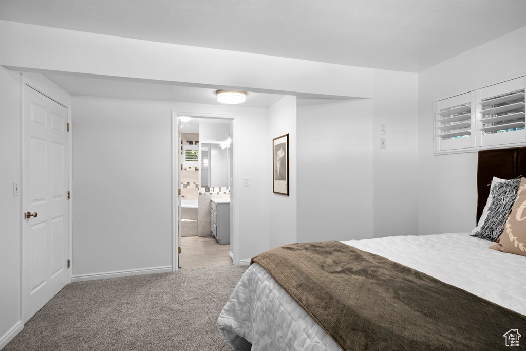 Carpeted bedroom featuring baseboards and ensuite bath