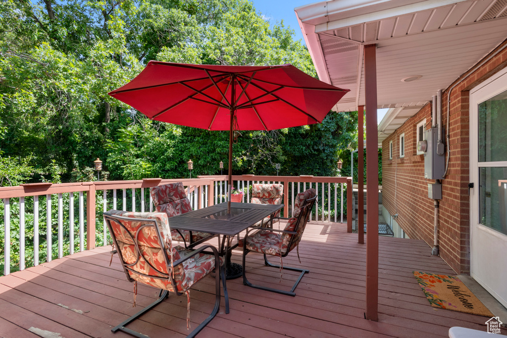 Wooden deck with outdoor dining area and view of scattered trees