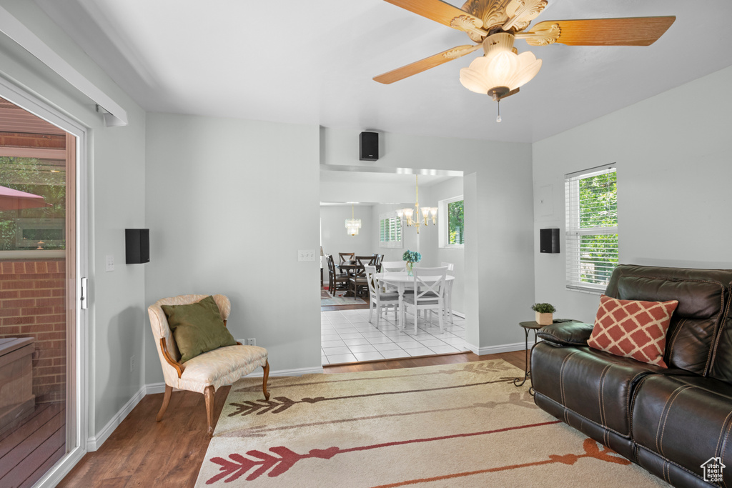 Living room featuring wood finished floors, a chandelier, baseboards, and a ceiling fan