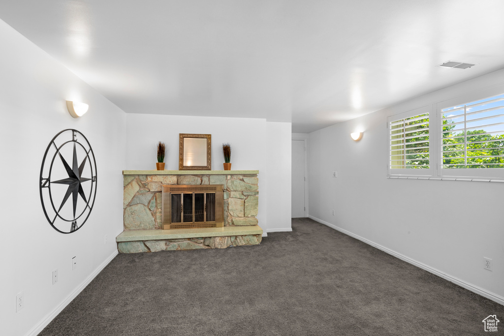 Unfurnished living room featuring carpet floors, a fireplace, and baseboards