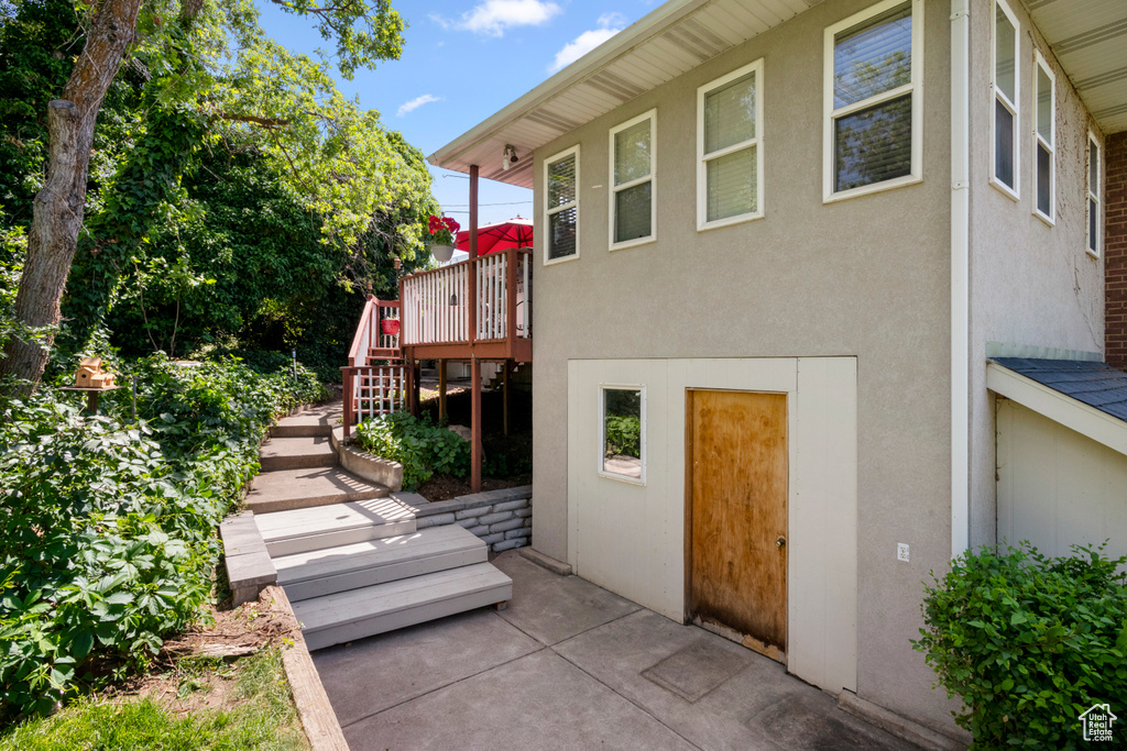 Rear view of house with stairs, stucco siding, a deck, and a patio