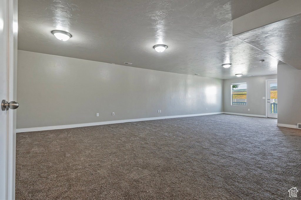 Spare room featuring carpet flooring, baseboards, and a textured ceiling