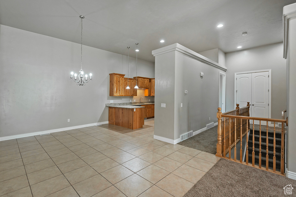 Kitchen featuring brown cabinetry, a chandelier, light tile patterned floors, recessed lighting, and baseboards