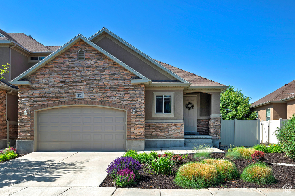Craftsman-style house with stone siding, stucco siding, driveway, and a garage