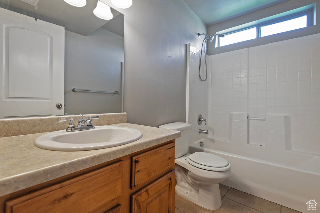 Bathroom with toilet, vanity,  shower combination, and tile patterned flooring