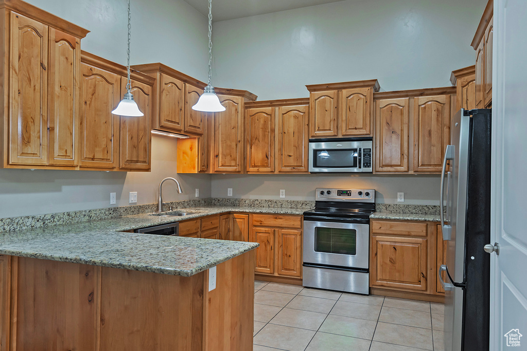 Kitchen featuring stainless steel appliances, a sink, a peninsula, light tile patterned floors, and hanging light fixtures