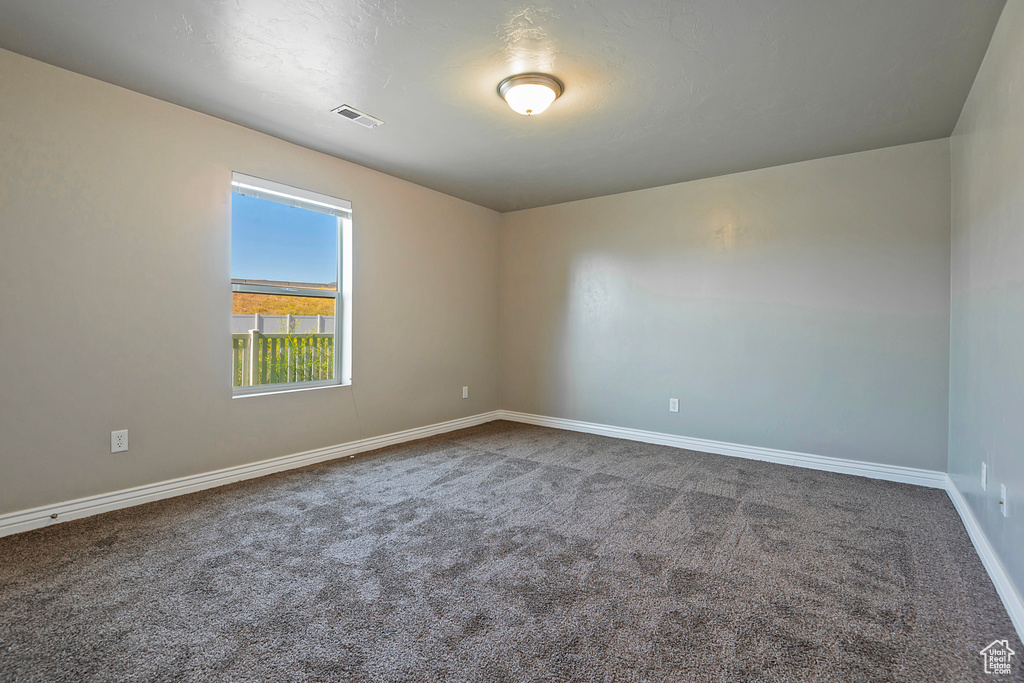 Spare room featuring dark carpet and baseboards