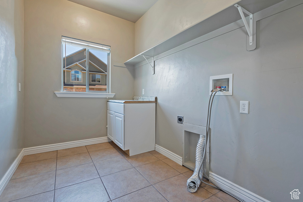 Laundry area with electric dryer hookup, washer hookup, light tile patterned floors, and baseboards