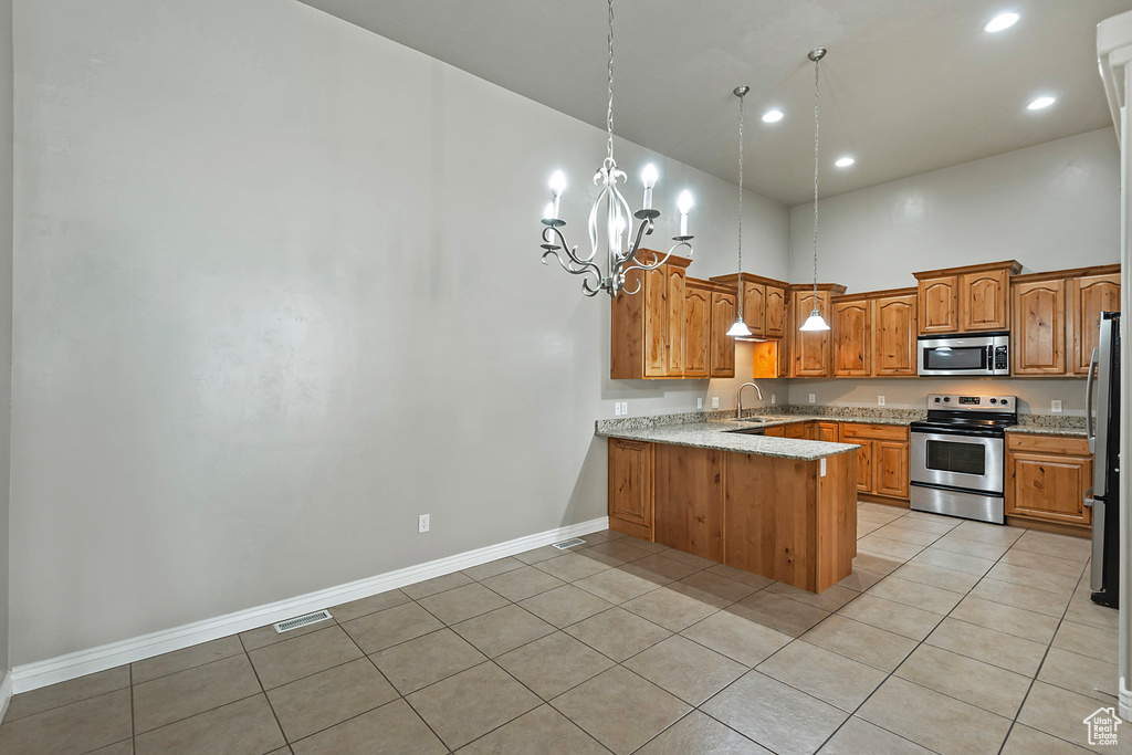 Kitchen with appliances with stainless steel finishes, a peninsula, a sink, baseboards, and a chandelier