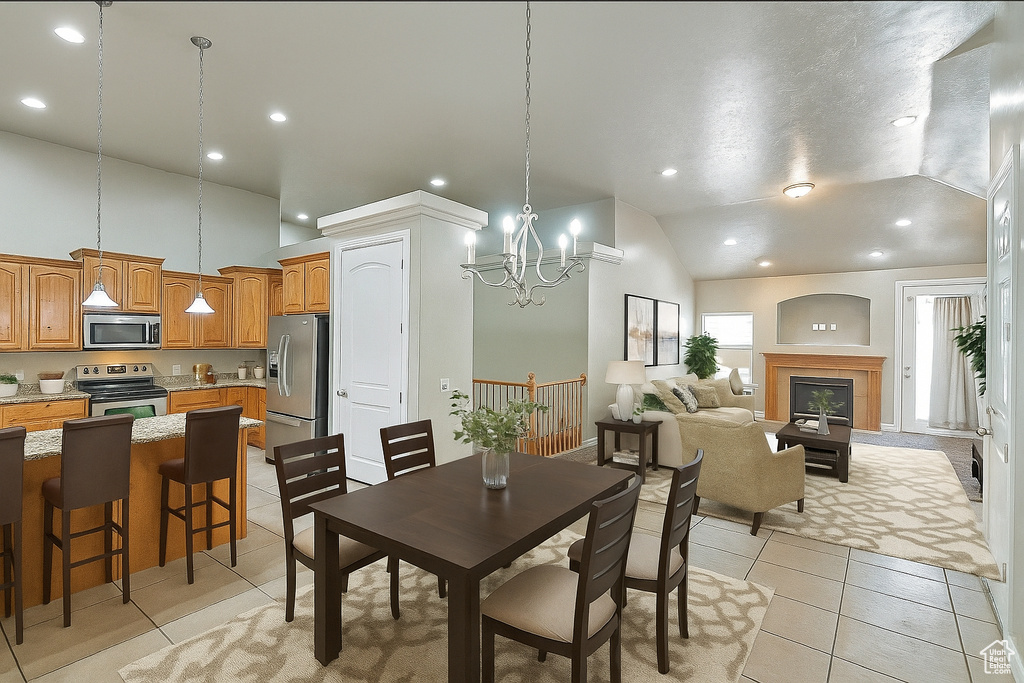 Dining area featuring light tile patterned floors, recessed lighting, high vaulted ceiling, a chandelier, and a glass covered fireplace