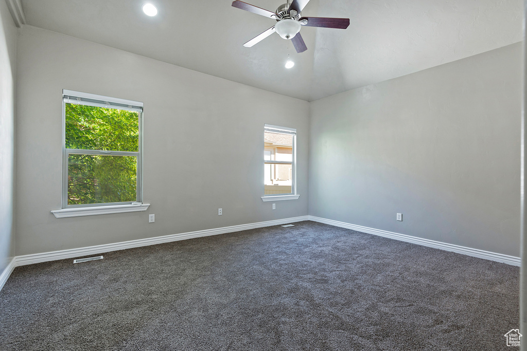 Empty room featuring dark carpet, ceiling fan, baseboards, recessed lighting, and vaulted ceiling