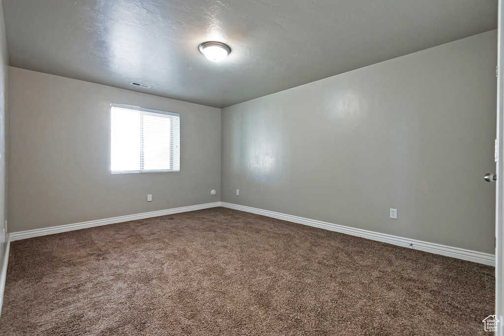 Spare room with dark carpet and baseboards