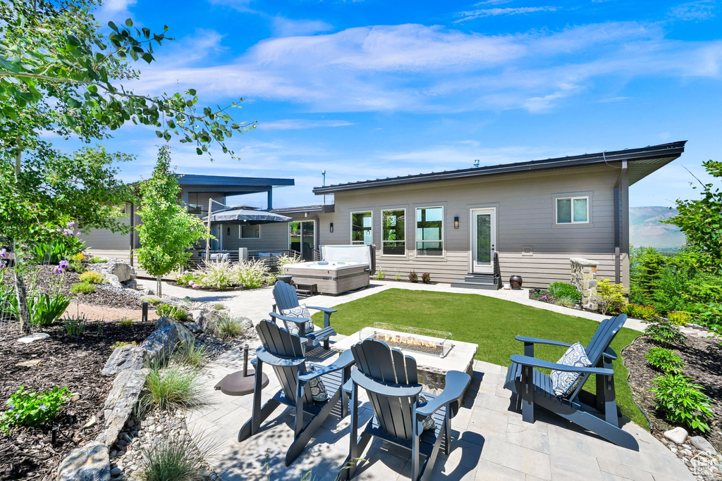 Back of property featuring a hot tub, an outdoor fire pit, entry steps, and a patio area
