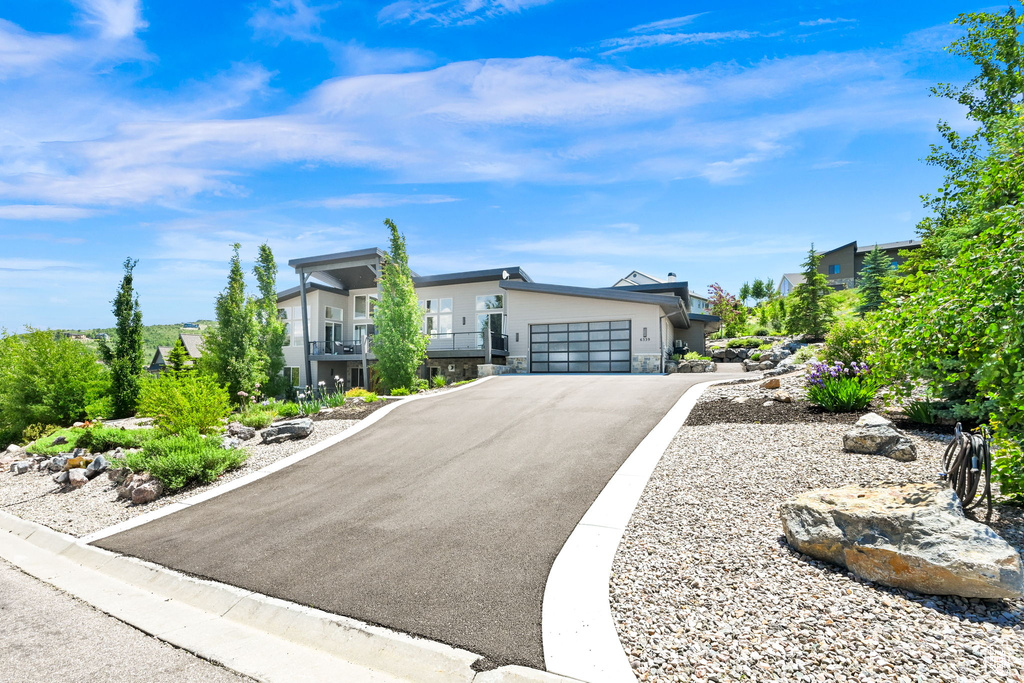 Contemporary home with stone siding, a garage, and asphalt driveway
