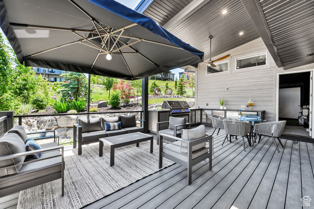 Wooden deck featuring an outdoor hangout area and a grill