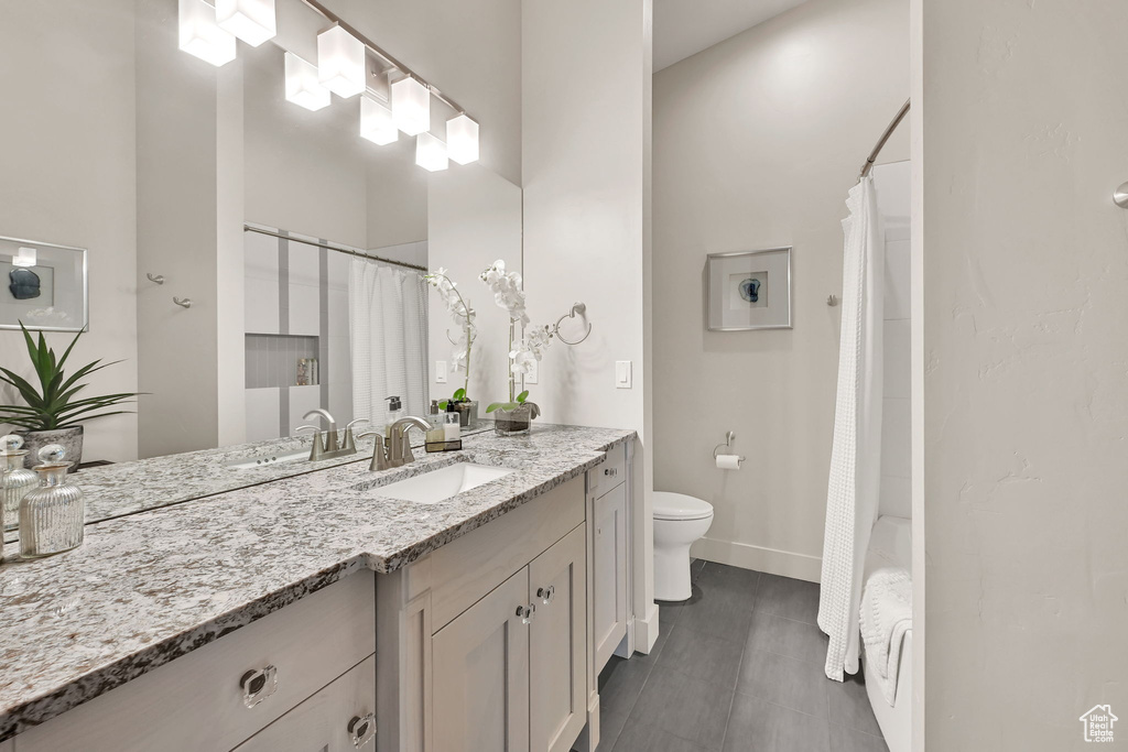 Full bathroom with vanity, toilet, baseboards, and shower / bath combo