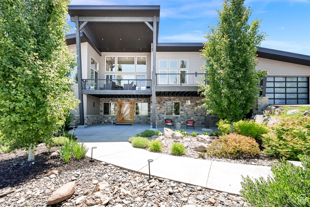 Back of property featuring a patio and stone siding