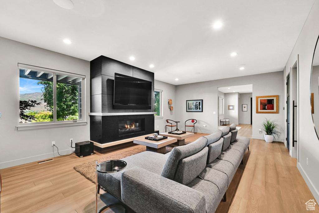 Living room with light wood-style floors, a fireplace, baseboards, and recessed lighting