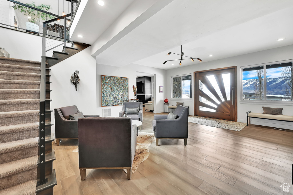 Living room with stairway, light wood-style floors, recessed lighting, and a chandelier