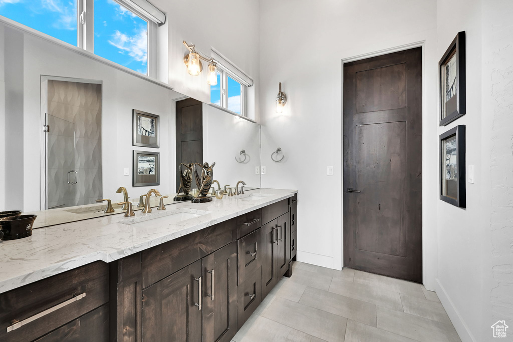 Full bath with double vanity, baseboards, and a shower