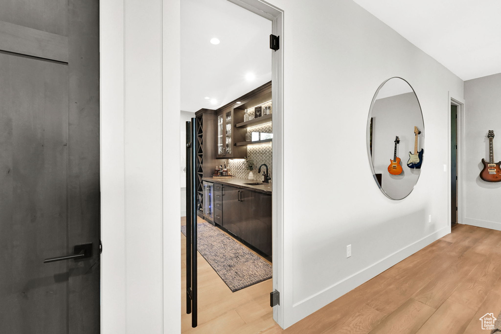 Hallway with a sink, light wood-style flooring, baseboards, and recessed lighting