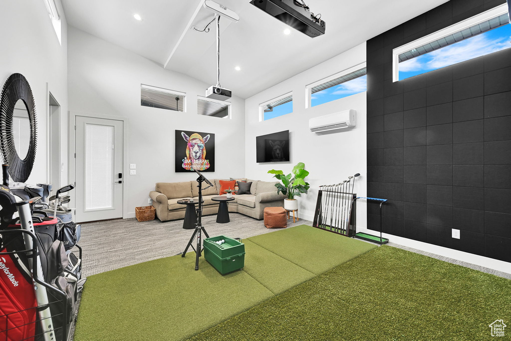 Living area featuring a wall mounted air conditioner, a high ceiling, baseboards, recessed lighting, and wood finished floors