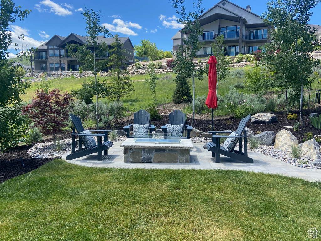 View of green lawn featuring a patio and an outdoor fire pit