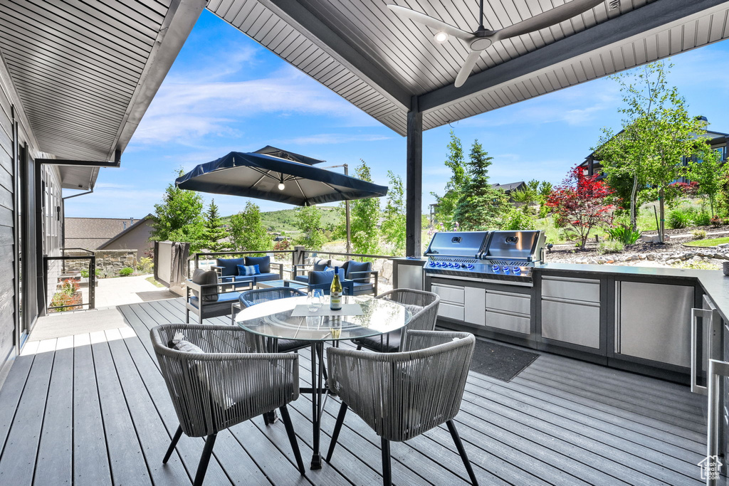 Wooden deck with a ceiling fan, outdoor lounge area, and outdoor dining area