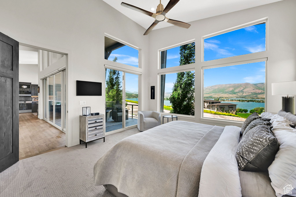 Carpeted bedroom with high vaulted ceiling, access to exterior, and ceiling fan