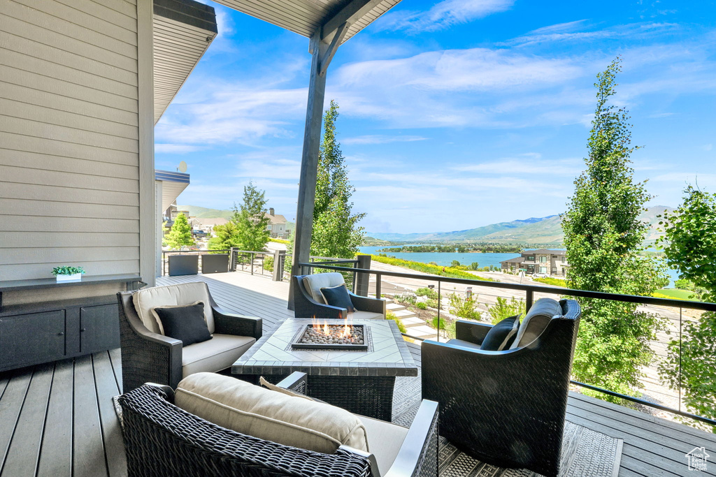 Wooden deck featuring a water and mountain view and an outdoor living space with a fire pit