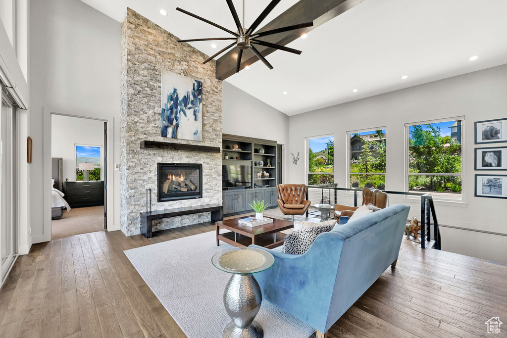 Living area featuring high vaulted ceiling, a fireplace, hardwood / wood-style flooring, and recessed lighting