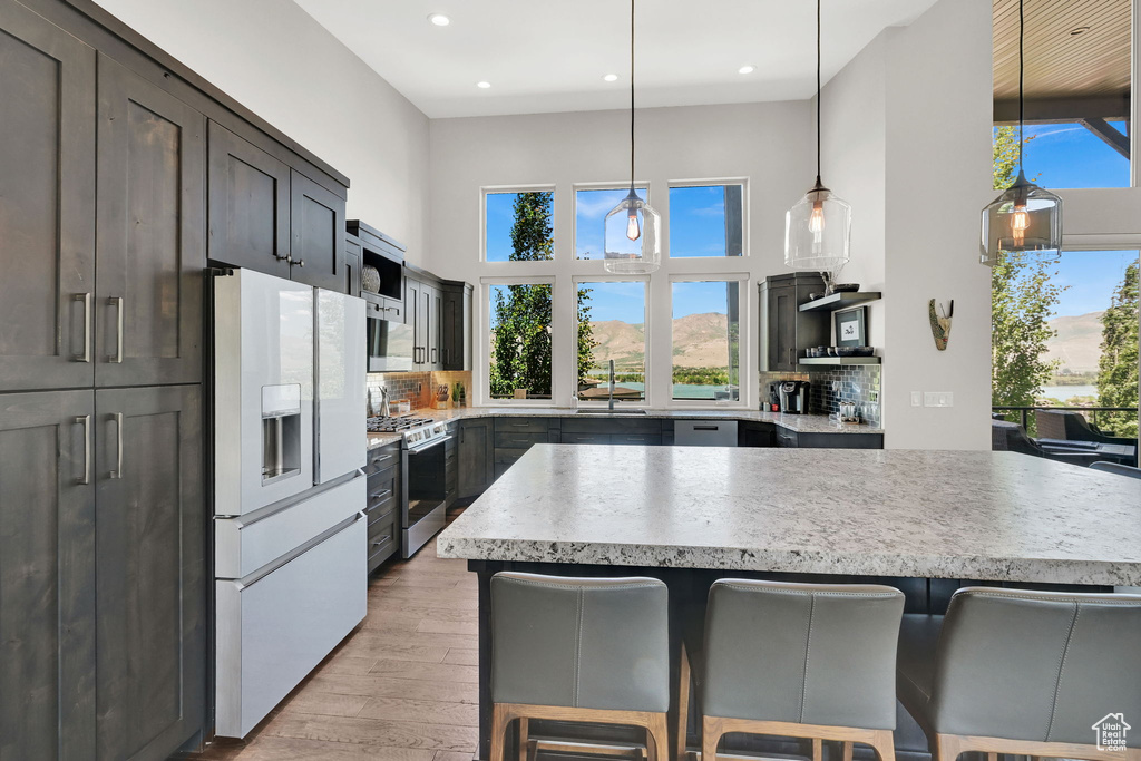 Kitchen featuring white refrigerator with ice dispenser, stainless steel gas range, a sink, a kitchen breakfast bar, and decorative backsplash
