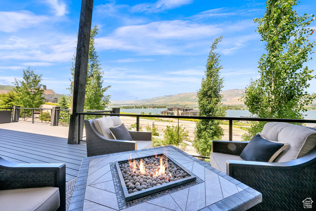 Wooden deck with a fire pit and a water and mountain view