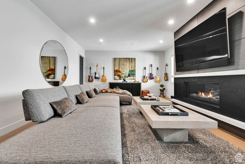 Living area featuring recessed lighting, a glass covered fireplace, wood finished floors, and baseboards