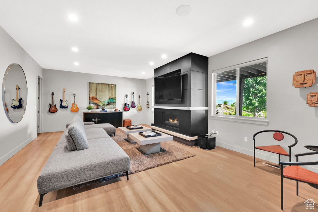 Living room with light wood-style flooring, baseboards, a fireplace, and recessed lighting