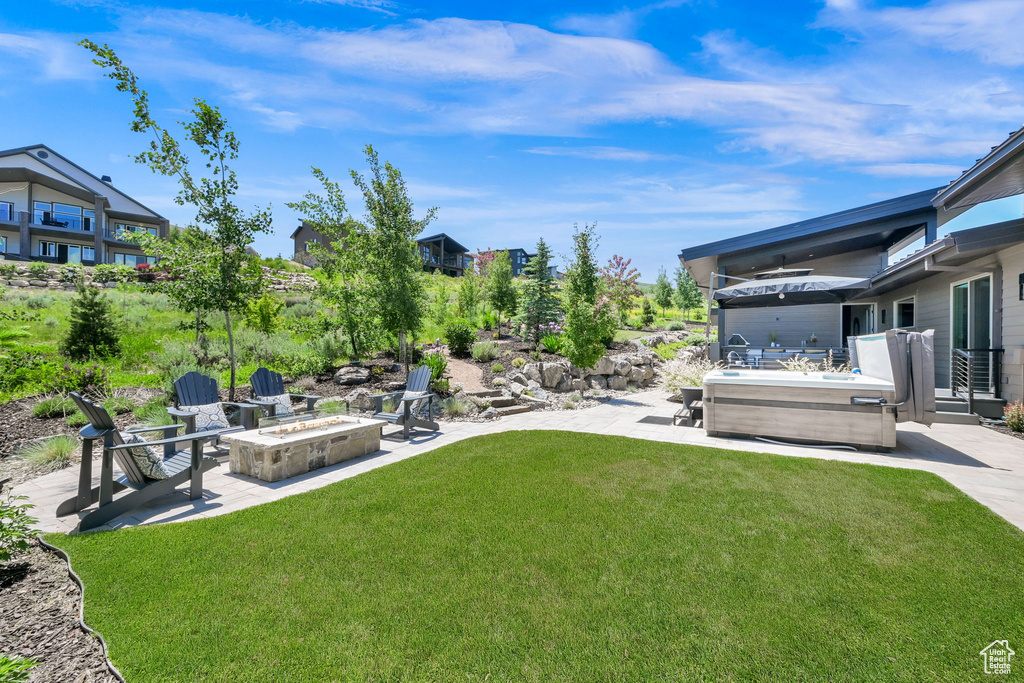 View of grassy yard with an outdoor fire pit and a patio
